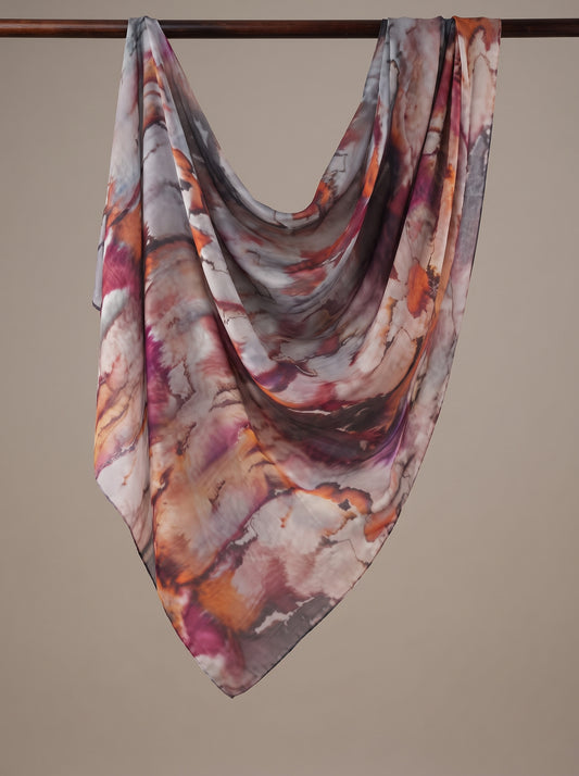 A lightweight square scarf with an abstract marbled pattern in shades of orange, purple, pink, and gray, draped over a dark wooden hanger against a solid beige background.